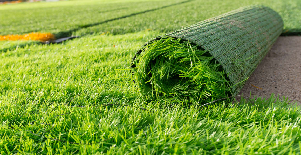 A roll of artificial turf being laid in a garden