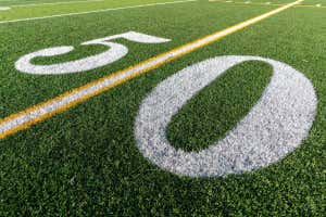 2JRB8F9 Synthetic turf football field fifty, 50, yard line in white.